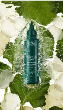 A bottle of aveda botanical repair hair treatment surrounded by green leaves and splashes of water. - Scott J Salons in New York, NY
